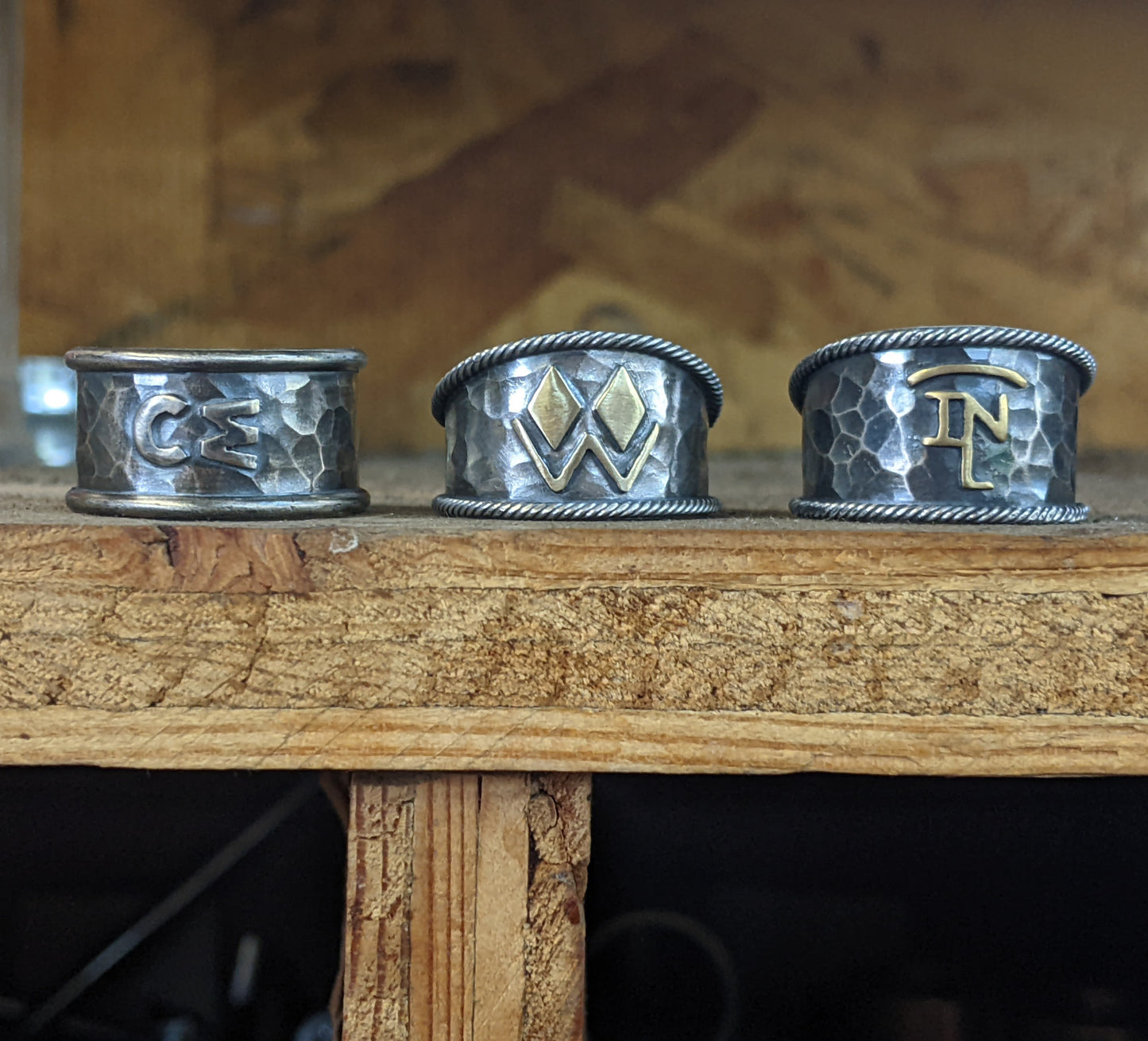 Three custom-made sterling silver western brand rings, one with a silver overlay and two with a brass overlay.