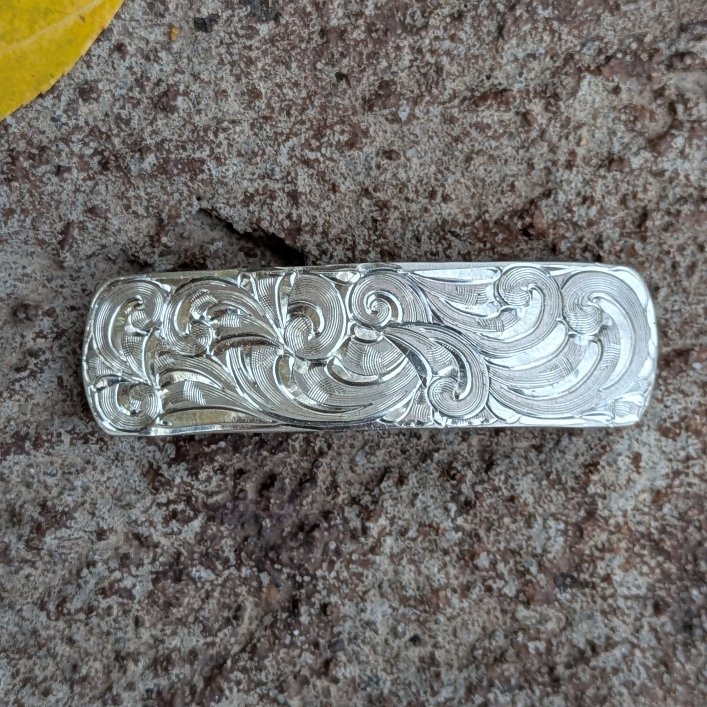 Hand-engraved silver hair clip on a rustic background