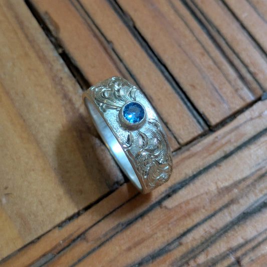 Silver ring with a blue gemstone on a wooden surface