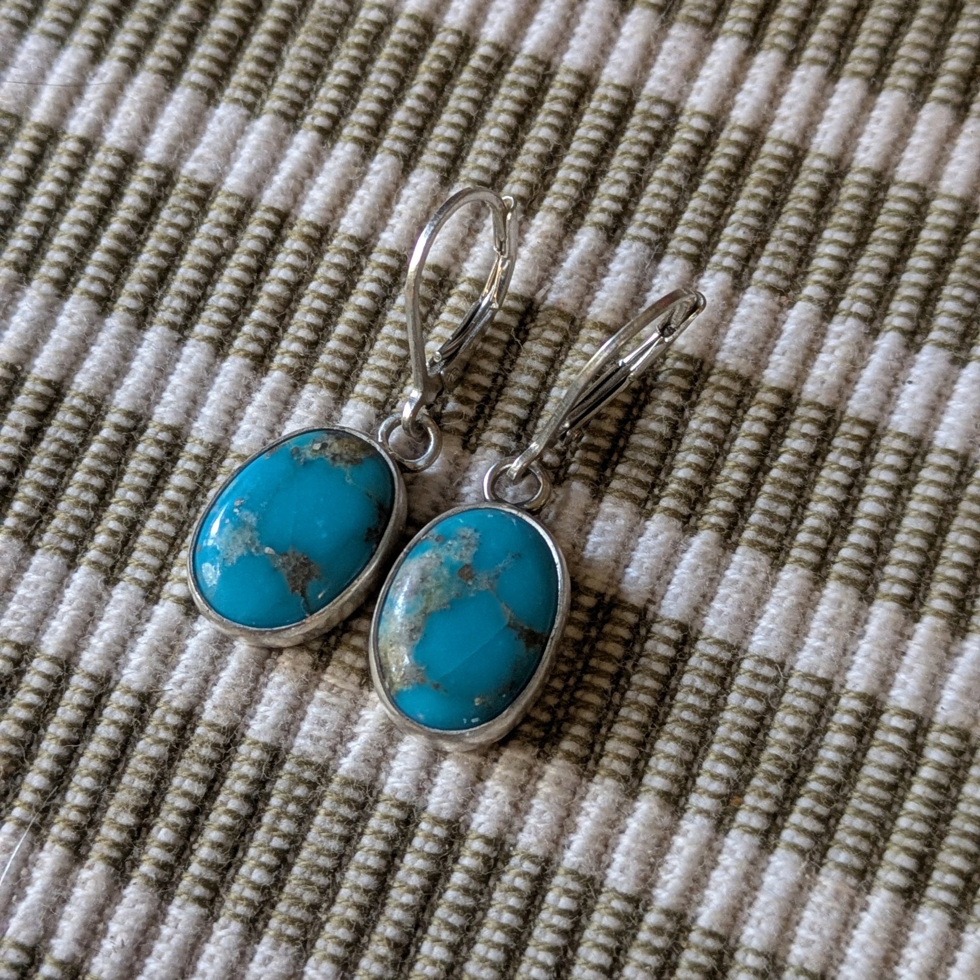 Turquoise earrings on a textured fabric background