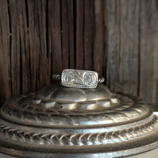 Silver ring on a decorative metal box with a wooden background