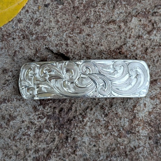 Hand-engraved silver hair clip on a rustic background